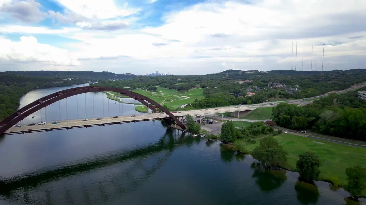 Aerial view of a bridge crossing a river surrounded by green hills
